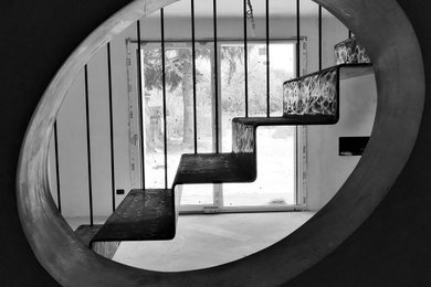 Diseño de sala de estar abierta urbana con paredes negras, marco de chimenea de yeso y suelo negro