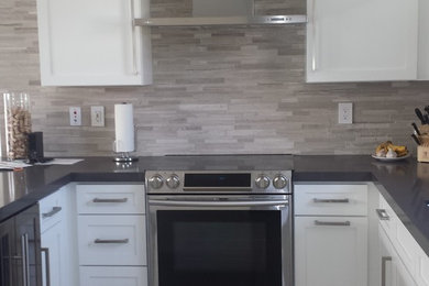 Eat-in kitchen - mid-sized modern u-shaped porcelain tile eat-in kitchen idea in Miami with an undermount sink, shaker cabinets, white cabinets, quartz countertops, beige backsplash, stone tile backsplash, stainless steel appliances and a peninsula