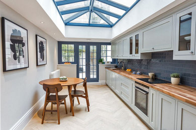 Inspiration for a classic kitchen/diner in London with a submerged sink, shaker cabinets, grey cabinets, wood worktops, blue splashback, metro tiled splashback and no island.