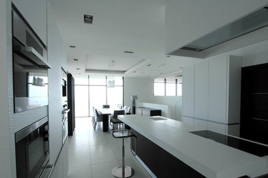 Large contemporary single-wall eat-in kitchen in Other with an undermount sink, white cabinets, white splashback, with island and white floor.