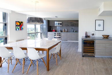 Example of a mid-sized trendy u-shaped open concept kitchen design in Miami with an undermount sink, flat-panel cabinets, gray cabinets, solid surface countertops, gray backsplash and an island