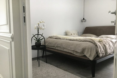 Modelo de dormitorio principal escandinavo pequeño con paredes blancas, suelo de baldosas de porcelana y suelo gris