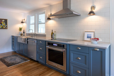 Transitional galley medium tone wood floor eat-in kitchen photo in Boston with shaker cabinets, blue cabinets, quartz countertops, white backsplash, ceramic backsplash, stainless steel appliances and gray countertops