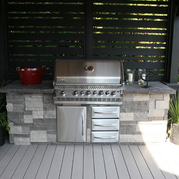 A large low maintenance deck with a BBQ area with a shade roof over it.