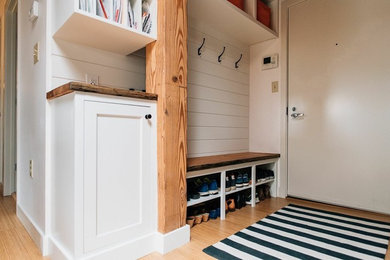 Example of a mid-sized transitional medium tone wood floor and brown floor mudroom design in Other with white walls