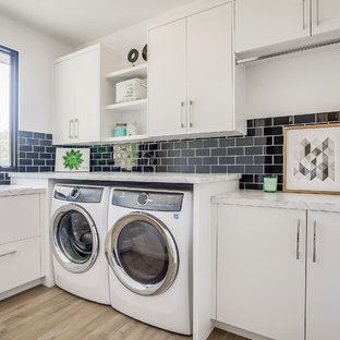 Photo of a contemporary l-shaped separated utility room in Grand Rapids with a built-in sink, flat-panel cabinets, white cabinets, laminate countertops, white walls, medium hardwood flooring, a side by side washer and dryer, brown floors and white worktops.