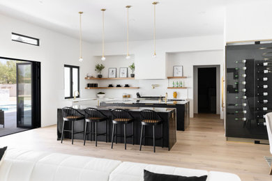 Exempel på ett mycket stort modernt svart svart kök med öppen planlösning, med släta luckor, vita skåp, bänkskiva i kvartsit, vitt stänkskydd, stänkskydd i sten, integrerade vitvaror, ljust trägolv, flera köksöar, en undermonterad diskho och brunt golv