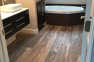 Inspiration for a large contemporary master porcelain tile drop-in bathtub remodel in Bridgeport with flat-panel cabinets, dark wood cabinets, beige walls, a vessel sink and quartz countertops