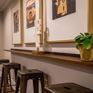 This is an example of a classic fully buried basement in Detroit with grey walls, vinyl flooring, a two-sided fireplace, a wooden fireplace surround and brown floors.