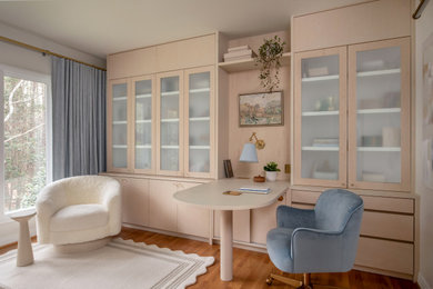 Example of a mid-sized transitional built-in desk light wood floor and beige floor home office design in Raleigh with white walls