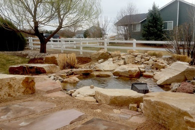 Photo of a large rustic drought-tolerant and full sun side yard stone pond in Denver for winter.