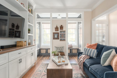 Imagen de sala de estar tradicional renovada con paredes beige, suelo de madera en tonos medios y pared multimedia