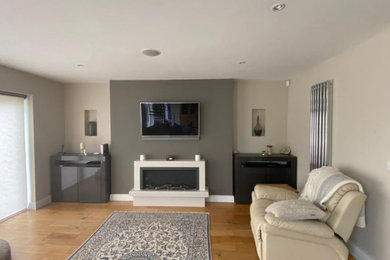 Inspiration for a medium sized contemporary formal open plan living room in Essex with grey walls, light hardwood flooring and a wall mounted tv.