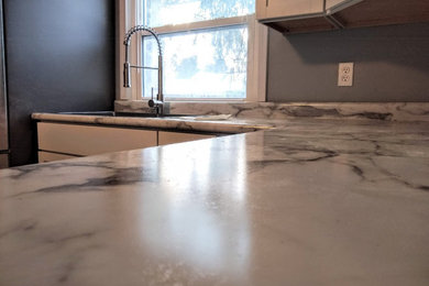Example of a mid-sized classic l-shaped vinyl floor and gray floor eat-in kitchen design in Detroit with a drop-in sink, shaker cabinets, white cabinets, laminate countertops, white backsplash, travertine backsplash, stainless steel appliances and gray countertops