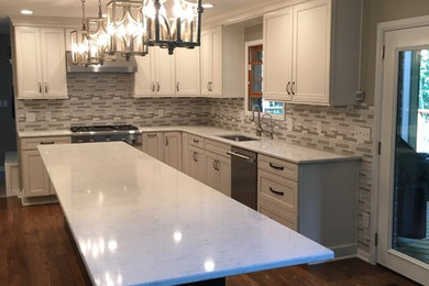 Example of a mid-sized danish u-shaped medium tone wood floor and brown floor open concept kitchen design in Cincinnati with an undermount sink, recessed-panel cabinets, white cabinets, quartz countertops, gray backsplash, porcelain backsplash, stainless steel appliances, an island and white countertops