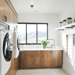 Inspiration for a contemporary l-shaped utility room in Salt Lake City with an integrated sink, flat-panel cabinets, white walls, a side by side washer and dryer, grey floors, white worktops and medium wood cabinets.