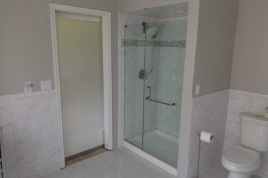 Inspiration for a mid-sized contemporary master white tile and marble tile marble floor and white floor bathroom remodel in Chicago with recessed-panel cabinets, white cabinets, a two-piece toilet, gray walls, an undermount sink, marble countertops, a hinged shower door and white countertops