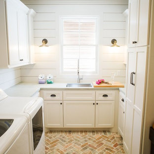 ヒューストンの中サイズのカントリー風おしゃれな洗濯室 (アンダーカウンターシンク、落し込みパネル扉のキャビネット、白いキャビネット、白い壁、レンガの床、左右配置の洗濯機・乾燥機、ベージュの床、グレーのキッチンカウンター、コンクリートカウンター) の写真