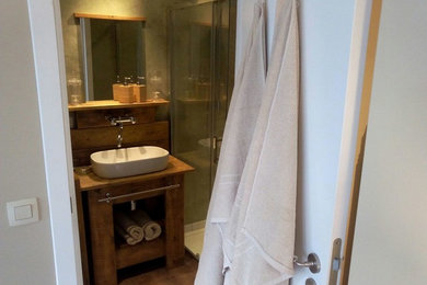 Idées déco pour une petite salle d'eau classique en bois clair avec un placard sans porte, WC suspendus, un carrelage vert, un mur vert, un sol en vinyl, un lavabo posé, un plan de toilette en bois, un sol marron et une cabine de douche à porte coulissante.