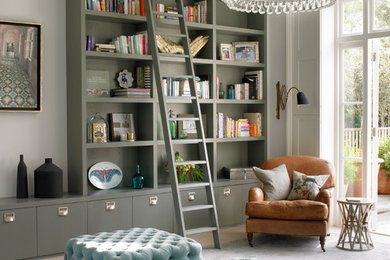 Transitional living room in London with a library, grey walls and light hardwood floors.