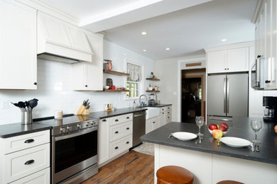 Enclosed kitchen - mid-sized transitional galley vinyl floor and brown floor enclosed kitchen idea in Philadelphia with a farmhouse sink, shaker cabinets, gray cabinets, quartz countertops, white backsplash, porcelain backsplash, stainless steel appliances and black countertops