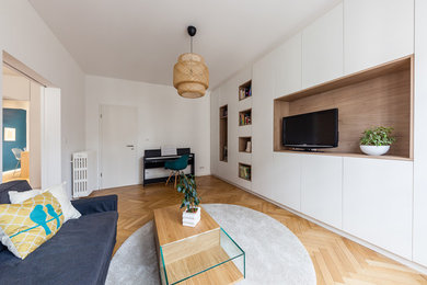 This is an example of a large contemporary open concept living room in Strasbourg with a library, white walls and light hardwood floors.