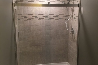 Sliding shower door - small modern master gray tile and porcelain tile ceramic tile and brown floor sliding shower door idea in Richmond with white cabinets, a two-piece toilet and gray walls