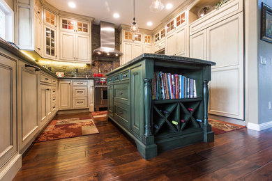 Inspiration for a mid-sized timeless u-shaped dark wood floor eat-in kitchen remodel in San Diego with beaded inset cabinets, beige cabinets, granite countertops, brown backsplash, stone tile backsplash, stainless steel appliances, an undermount sink and an island