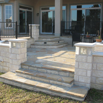 Modern flagstone patio w/ limestone walls, lighted glass block columns