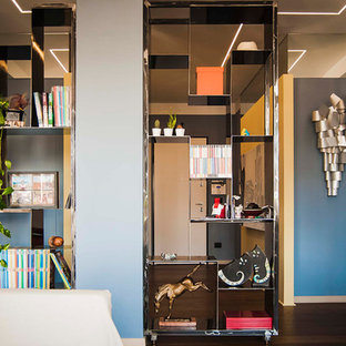 Cette photo montre un grand hall d'entrée éclectique avec un mur bleu, un sol en bois foncé, une porte simple, une porte en bois clair et un sol marron.