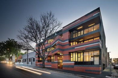 This is an example of a mid-sized modern three-storey brick red apartment exterior in Melbourne.