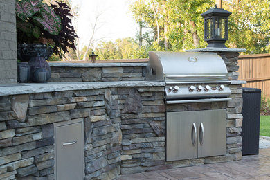 Mid-sized elegant backyard stone patio kitchen photo in Other with no cover
