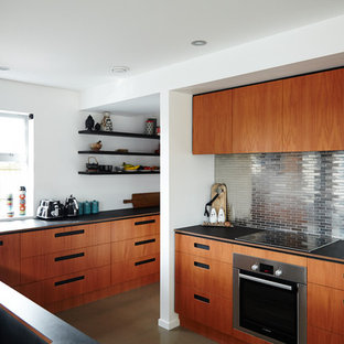 Huge contemporary kitchen pantry designs - Inspiration for a huge contemporary galley concrete floor and beige floor kitchen pantry remodel in Christchurch with an undermount sink, flat-panel cabinets, medium tone wood cabinets, solid surface countertops, metallic backsplash, metal backsplash, stainless steel appliances, a peninsula and black countertops