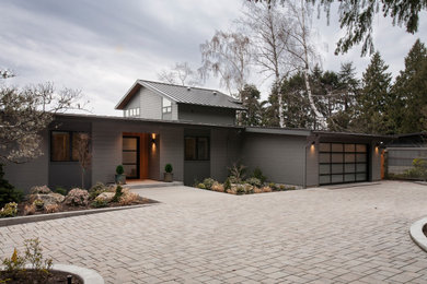 Inspiration for a large contemporary gray two-story concrete fiberboard and board and batten house exterior remodel in Seattle with a metal roof, a shed roof and a black roof