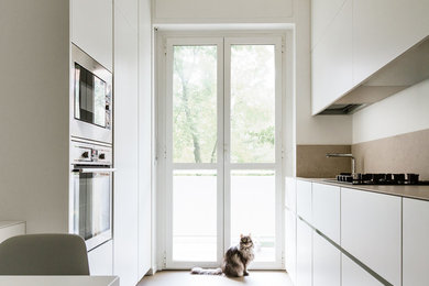 Esempio di una cucina minimal chiusa e di medie dimensioni con lavello sottopiano, ante lisce, ante bianche, paraspruzzi beige, elettrodomestici in acciaio inossidabile, penisola, pavimento beige, top beige, top in pietra calcarea, paraspruzzi in pietra calcarea e pavimento in gres porcellanato