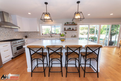Mid-sized country l-shaped eat-in kitchen in Los Angeles with an undermount sink, shaker cabinets, white cabinets, quartzite benchtops, beige splashback, ceramic splashback, stainless steel appliances, medium hardwood floors, with island, beige floor and white benchtop.