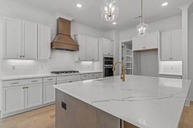 Example of a mid-sized classic l-shaped light wood floor eat-in kitchen design in Raleigh with an undermount sink, shaker cabinets, quartz countertops, white backsplash, porcelain backsplash, stainless steel appliances, an island and white countertops