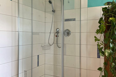 Kleines Modernes Duschbad mit Eckdusche, weißen Fliesen, Porzellanfliesen, weißer Wandfarbe, Porzellan-Bodenfliesen, beigem Boden und Falttür-Duschabtrennung in Sonstige