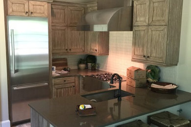 This is an example of a small transitional u-shaped kitchen in Other with flat-panel cabinets, quartz benchtops and stainless steel appliances.