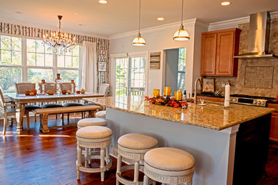 Example of an arts and crafts medium tone wood floor eat-in kitchen design in Chicago with a single-bowl sink, beige backsplash, stone tile backsplash, stainless steel appliances and an island
