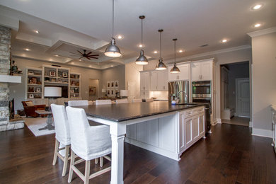 Inspiration for a transitional dark wood floor kitchen remodel in Little Rock with an undermount sink, shaker cabinets, white cabinets, granite countertops, white backsplash, subway tile backsplash, stainless steel appliances and an island