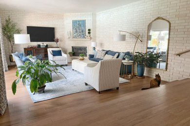 Imagen de salón abierto de tamaño medio con paredes beige, suelo de madera en tonos medios, chimenea de esquina y ladrillo