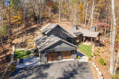 Mountain style black two-story wood and board and batten exterior home photo in Other with a mixed material roof and a gray roof
