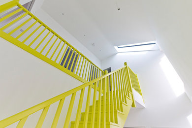 Design ideas for a mid-sized contemporary painted wood straight staircase in Hertfordshire with wood railing.