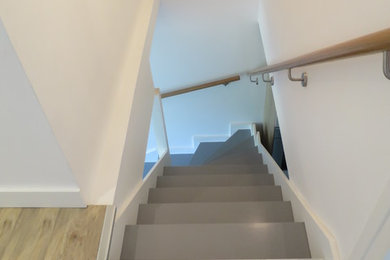 Trendy painted l-shaped glass railing staircase photo in Lyon with painted risers
