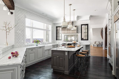 This is an example of a traditional u-shaped separate kitchen in New York with a farmhouse sink, raised-panel cabinets, white splashback, subway tile splashback, stainless steel appliances, with island and black floor.