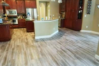 Design ideas for a large traditional galley open plan kitchen in Tampa with raised-panel cabinets, dark wood cabinets, granite benchtops, stainless steel appliances, multiple islands and porcelain floors.