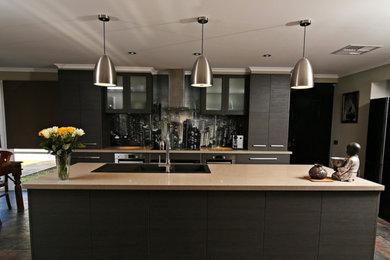 Inspiration for a mid-sized contemporary single-wall open plan kitchen in Melbourne with flat-panel cabinets, dark wood cabinets, limestone floors, with island, a double-bowl sink, limestone benchtops, black splashback, glass sheet splashback and black appliances.