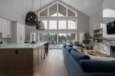 Huge transitional open concept light wood floor and vaulted ceiling living room photo in Vancouver with gray walls, a standard fireplace, a stone fireplace and a wall-mounted tv