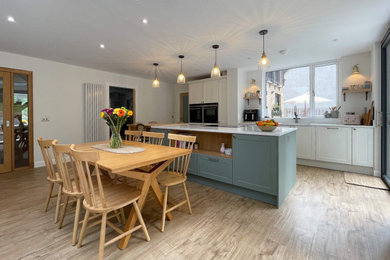 Inspiration for a medium sized modern single-wall open plan kitchen in Other with a double-bowl sink, recessed-panel cabinets, green cabinets, engineered stone countertops, white splashback, window splashback, black appliances, medium hardwood flooring, an island, brown floors and white worktops.